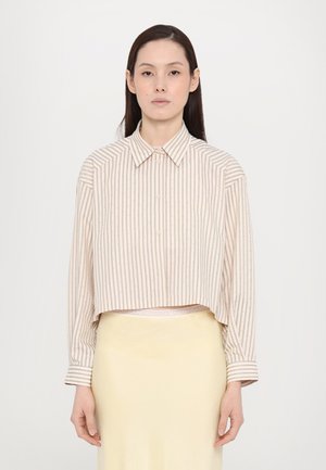 Cropped button-up shirt with vertical stripes in beige and pastel colors, featuring long sleeves and a collar, worn over a yellow skirt.