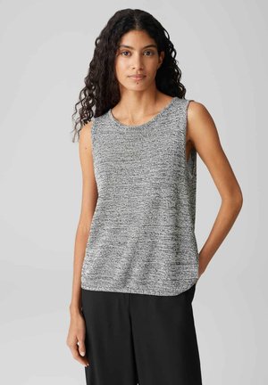 Débardeur gris et blanc en tricot texturé avec un col rond et une coupe ample, associé à un pantalon noir. Pas d'embellissements visibles.