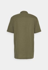 Camisa de manga corta en verde oliva, confeccionada con una tela ligera. Cuenta con cuello y dobladillo recto con aberturas laterales.