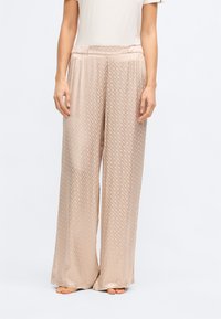 Μπεζ παντελόνια με φαρδιά πόδια και διακριτό διαμαντένιο σχέδιο, κατασκευασμένα από απαλή, ελαφριά ύλη. Διαθέτουν ελαστική μέση για μεγαλύτερη άνεση.