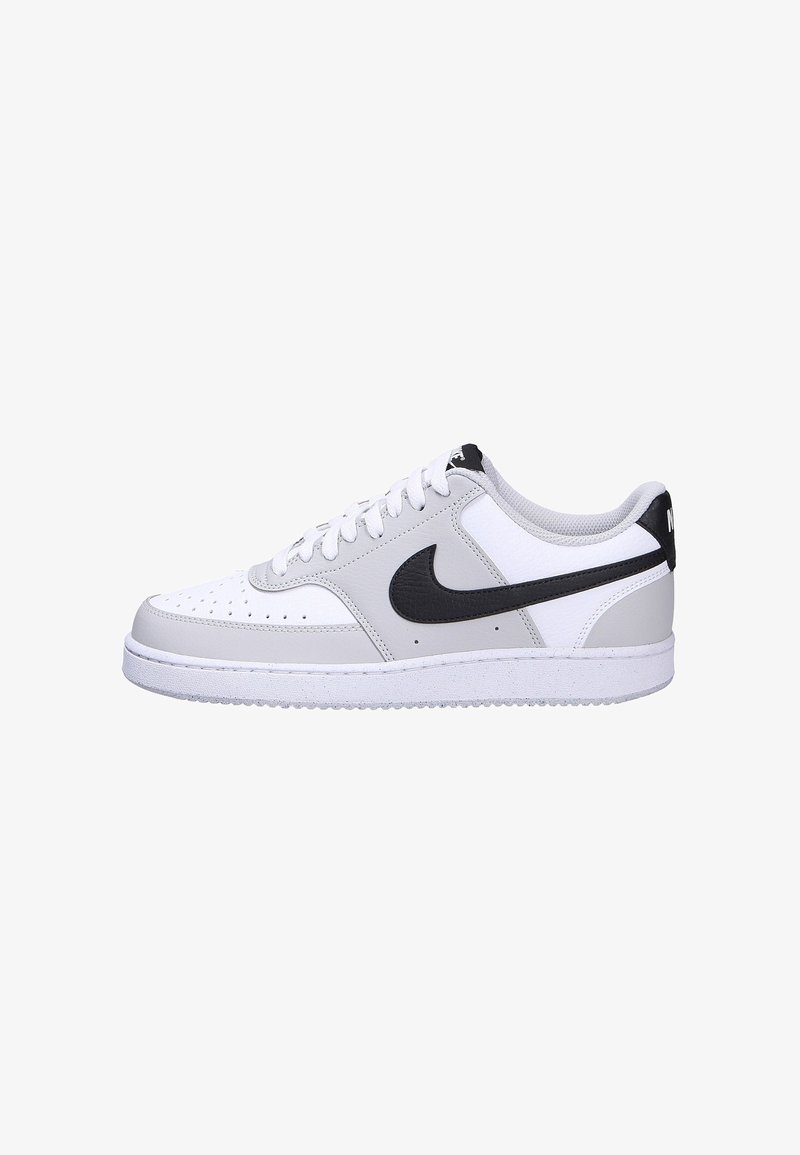 Baskets Nike blanches et grises avec logo Swoosh noir, lacets blancs et semelle en caoutchouc, vues de côté sur fond blanc.