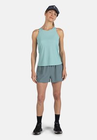 Ljusblå ärmlös tanktop, grå shorts, svarta strumpor och svarta löparskor. Kappen är marinblå med en logotyp på framsidan.