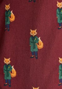 Rakstainais audums ar atkārtotiem lapsu tēliem, kuriem ir zaļas jakas, zilas bikses un melnas kurpes uz bordo tekstūras fona.