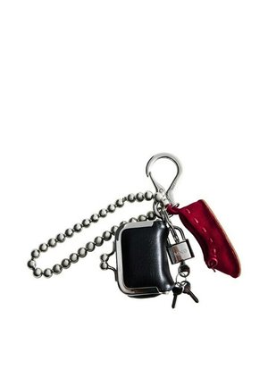 Portachiavi con una catena a sfere d'argento, un portamonete nero, un piccolo lucchetto d'argento con chiavi e un ciondolo a forma di scarpa rossa in pelle attaccato a un moschettone d'argento.