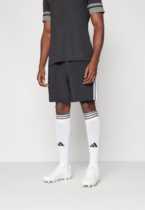 Black athletic shirt, black shorts, white high socks with gray stripes, and white cleats with gold accents. Features Adidas branding.