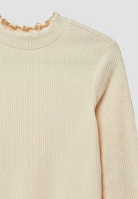 Rippendes Langarmoberteil in hellem Creme mit einem Rüschenausschnitt. Hergestellt aus weichem Stoff, mit vertikalen Streifen und einer taillierten Silhouette.