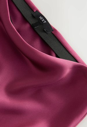 Bordeaux satijnen stof met een gladde textuur, voorzien van een zwarte elastische tailleband en een label met de tekst "NEXT" aan de binnenkant.