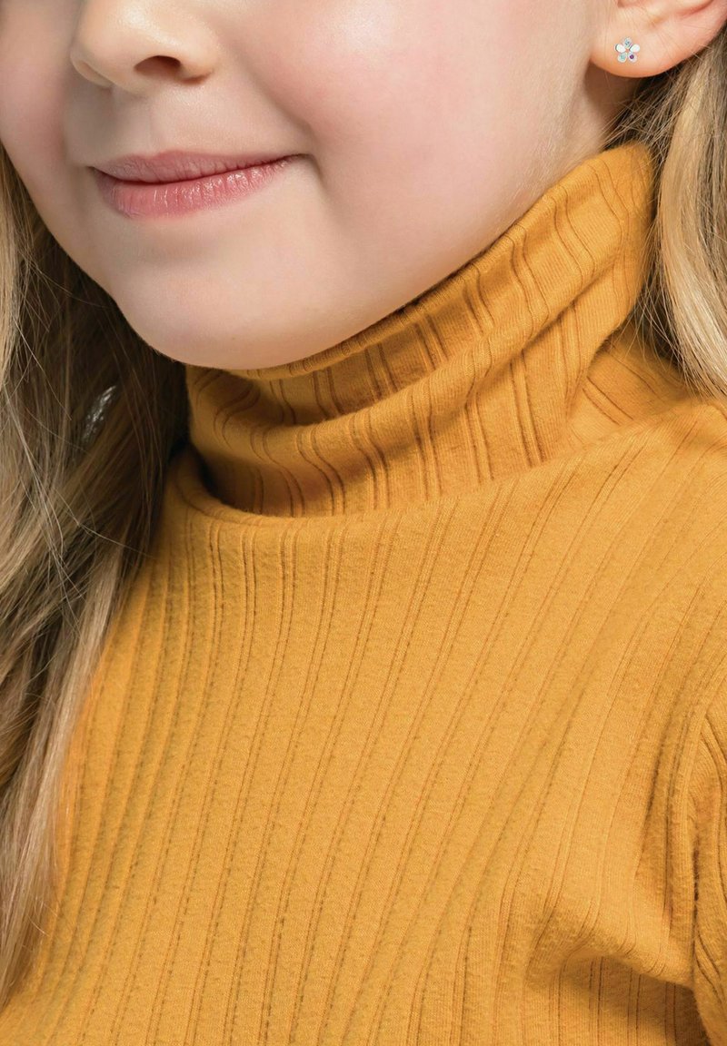 Suéter de cuello alto ribeteado en color mostaza con un cuello ajustado. Textura suave y líneas verticales sutiles. Pendiente en forma de flor pequeño visible.