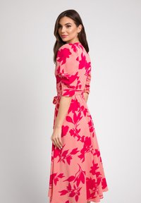 Różowa sukienka z dużym kwiatowym nadrukiem w intensywnym fuksjowym kolorze, z bufkowymi rękawami i paskiem w talii. Gładki materiał, projekt do kolan.