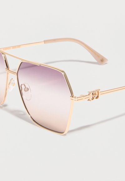 Γυαλιά ηλίου με χρυσό πλαίσιο, μεγάλα εξαγωνικά φακούς με βαθμιαία απόχρωση μωβ και ρυθμιζόμενες μύτες στη μύτη, σε λευκό φόντο.