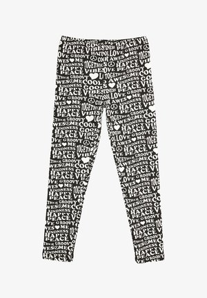 Sorte leggings med et gentagende hvidt tekstmønster, der indeholder ord som "venlighed", "fred" og "kærlighed". Strækbart stof, tætsiddende design.