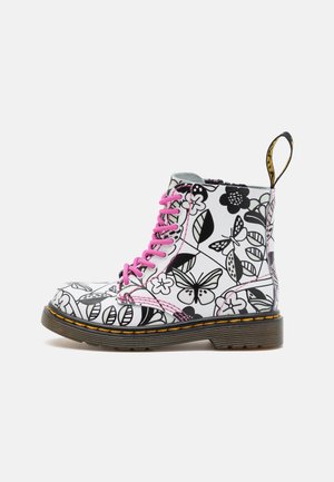 Stivale in pelle bianca con motivi floreali e farfalle nere, lacci rosa, cuciture gialle e suola spessa marrone.