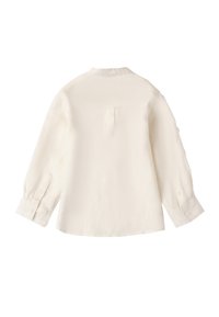 Camisa de manga larga color crema claro, hecha de una tela texturizada, con cuello mao, puños abotonados y un pliegue trasero.