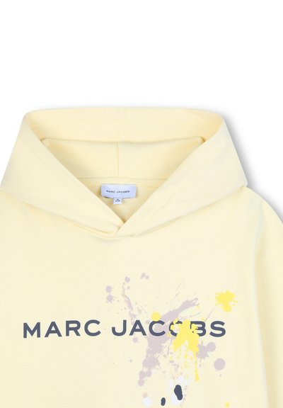 Lichtgele hoodie met een grafisch ontwerp met spetters in grijs, geel en wit, en de tekst "MARC JACOBS" in vette zwarte letters.