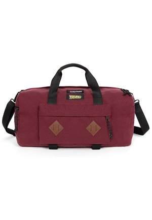 Sac de sport bordeaux avec des poignées noires et une bandoulière, comportant une poche avant avec des accents en diamant et un patch logo de marque.