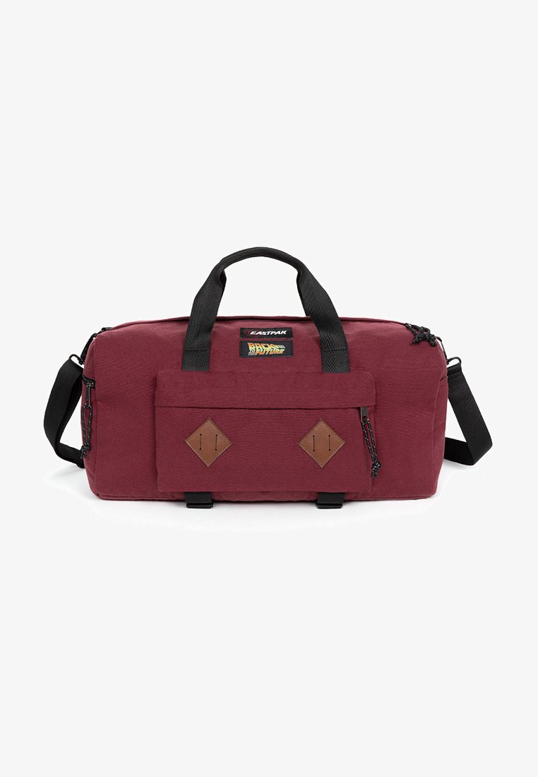 Maroon duffel bag with black handles and shoulder strap, featuring a front pocket with diamond accents and a branded logo patch.