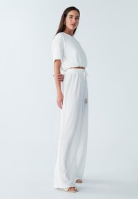Witte geribbelde twee-delige outfit met een cropped top met korte mouwen en losse, wijde broek met een verstelbare trekkoord in de taille.