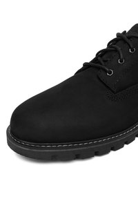 Pantofii din suede negru, cu vârful rotund, au șireturi negre, cusături contrastante și o talpă din cauciuc texturată.