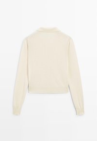Cream-colored knitted sweater with a polo collar, long sleeves, and a cropped design. Soft texture and ribbed cuffs and hem.