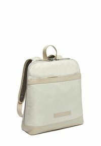 Mochila beige con un acabado de tela suave, detalles de cuero blando, un asa en la parte superior y correas ajustables, que cuenta con un compartimento principal con cremallera.