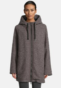 Oversized hooded coat in soft, textured gray fabric with a front zipper, contrast trim, and large pockets on each side.