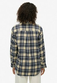 Chemise en flanelle à carreaux beige et bleu marine, manches longues, poignets boutonnés, détail de l'empiècement au dos, coupe décontractée, texture douce.