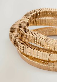 Guldmetall banglearmband med texturerad yta, som har sammanlänkade segment av varierande tjocklek och en hamrad finish.