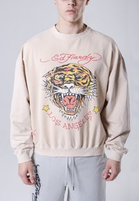 Felpa beige con una grande grafica di una tigre in colori vivaci, vestibilità ampia, polsini a coste e scollo rotondo, con testo e dettagli "Ed Hardy".