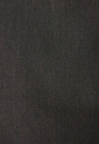 Tissu en denim noir avec une texture lisse, présentant un motif de toile en biais subtil sur la surface. Aucun motif ou accent visible.