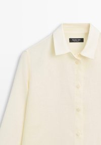 Roomkleurig overhemd met lange mouwen en knopen, met een puntige kraag, voorzien van een zwart "Massimo Dutti" label genaaid aan de binnenkant van de nek.