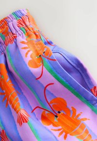 Violeta krāsā ar omāru rakstu īsie šorti, kuros attēloti oranži omāri un zaļas svītras. Elastīga jostas vieta ar savāktu detaļu un sānu kabatām.