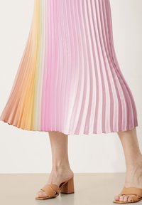 Gonna midi plissettata in un gradiente di colori pastello dall'arancione al rosa. Tessuto liscio e lucido con orlo svasato. Sandali marroni con tacco a blocco.