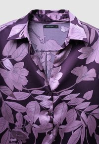 Camicia in satin di un profondo viola con motivo floreale in lavanda chiara, colletto a punta e chiusura con bottoni. Tessuto morbido e finitura liscia.