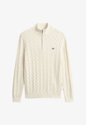 Roomkleurige kabelgebreide trui met een halve ritskraag en geribde zoom en manchetten. Heeft een klein logo op de borst.