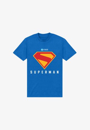 Camiseta de algodón azul con un gran logo de Superman en rojo y amarillo, con la palabra "SUPERMAN" impresa en letras blancas y negritas debajo.