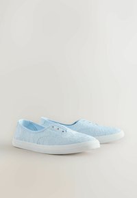 Baskets slip-on en dentelle bleu clair avec semelles en caoutchouc blanches et œillets, affichées côte à côte sur un fond neutre.