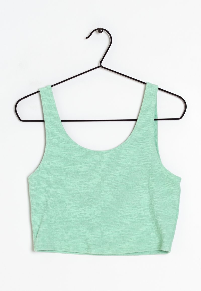 Haut court en tissu vert menthe texturé avec larges bretelles, suspendu sur un cintre en fil noir contre un fond blanc.