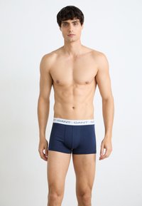 Boxeri de culoare bleumarin, cu un talie elastică albă pe care este înscris numele brandului. Confectionați dintr-un material neted și elastic. Design ajustat.