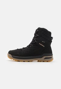 Schwarzer Wanderschuh mit einem Obermaterial aus Wildleder und Mesh, ausgestattet mit einem gepolsterten Kragen, Schnürverschlüssen und einer robusten Gummisohle mit einem braunen Profil.