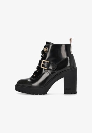 Black patent leather ankle boots with a high block heel, lace-up front, gold hardware accents, and a reinforced rubber sole.