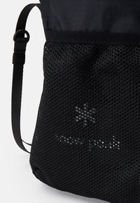 Borsa a rete nera con tessuto testurizzato, dotata di spallacci regolabili e un discreto motivo logo sul lato. Design leggero e traspirante.