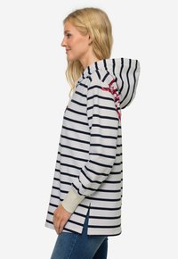 Sudadera a rayas con rayas horizontales en azul marino y blanco, gran capucha, aberturas laterales y acentos florales en el hombro, hecha de tela suave.