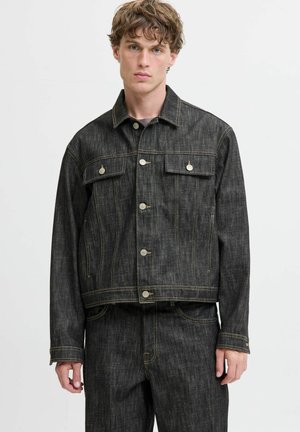 Mörk denimjacka med två bröstfickor, silverfärgade knappar och kontrasterande sömmar. Har en kortad passform och texturerad tyg.