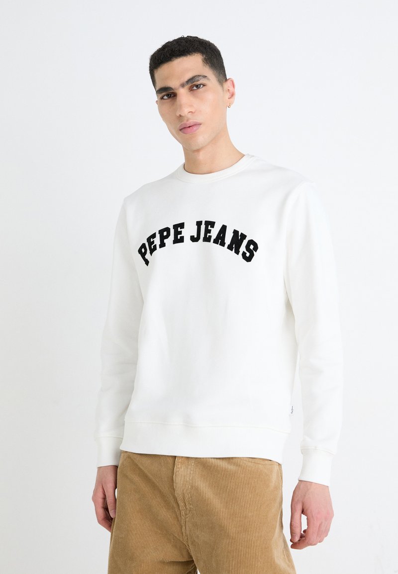 Witte sweatshirt met zwarte "PEPE JEANS" borduursel. Inclusief een ronde halslijn en geribbelde manchetten, gecombineerd met tan corduroy broek.