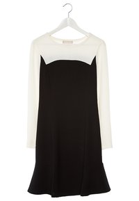 Robe à manches longues avec haut et manches blancs, corsage noir et jupe évasée, suspendue à un cintre blanc sur fond blanc.