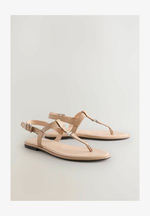 Beige Sandalen mit einem Zehensteg-Design, einem T-Riemen und Schnalle. Glattes, lederähnliches Material mit flacher Sohle und minimalistischen Akzenten.