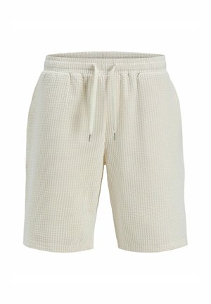 Shorts de couleur crème en tissu texturé avec un motif gaufré, dotés d'une taille élastique et d'un cordon de serrage pour un ajustement réglable.