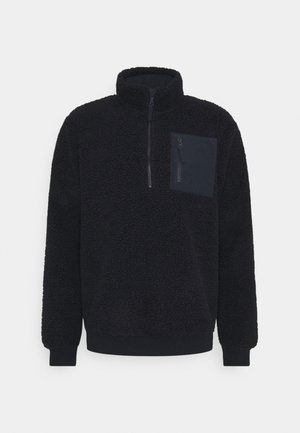 Black fleece pullover with a high collar, half-zip front, and a left chest pocket. Features textured fabric and ribbed cuffs.