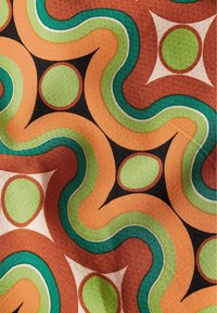 Motivo di tessuto con linee ondulate arancioni, verdi e turchesi con accenti circolari, su uno sfondo nero. Superficie texture.