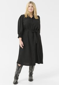 Black midi dress with button detail, belt at waist, and puffed sleeves. Paired with black cowboy boots featuring white floral embroidery.
